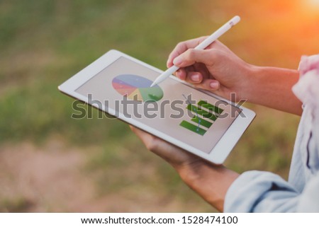 Close up businessman hand using tablet and pointing on summary report at office.Male businessman reviews a summary report on tablet.