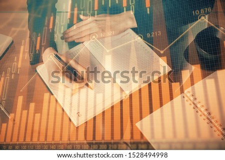 Forex chart hologram on hand taking notes background. Concept of analysis. Multi exposure