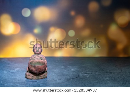Home decoration ornament. Little monk statue sitting holds bowl. Wallpaper background theme. Empty copy negative space for text.