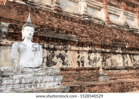 A white Buddha image with a background of clay bricks at Wat Yai Chai Mongkol. Phra Nakhon Si Ayutthaya, Thailand
