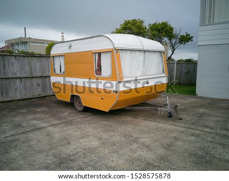 View of old yellow and white camper caravan parked in front of house
