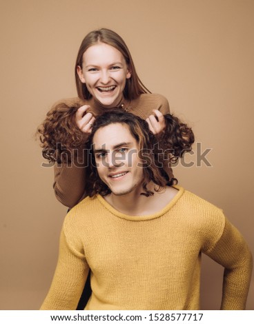 Funny time together. Joyful moments in pairs. Cheerful girl holding curly hair of boyfriend makes him funny hairstyles