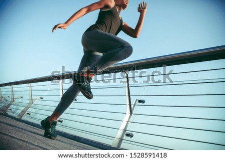 Cropped photo of a sportswoman exercising on the bridge and putting one knee up
