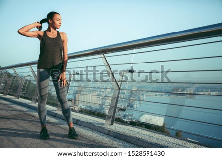 Calm thoughtful athlete standing on the bridge and touching ponytail while looking away. Website banner