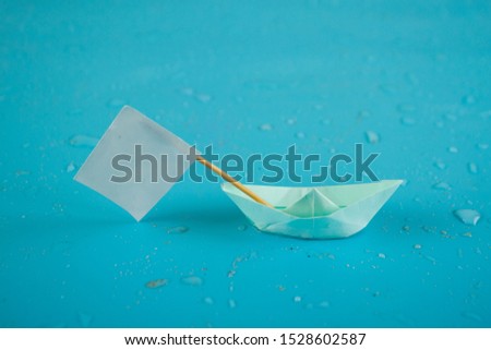 Beated paper ship with with flag. Blue background