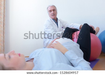 doctor with pregnant woman with gymnastic ball