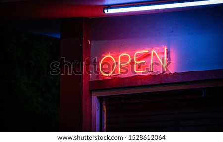 A vivid neon "open" sign in a store-front window.