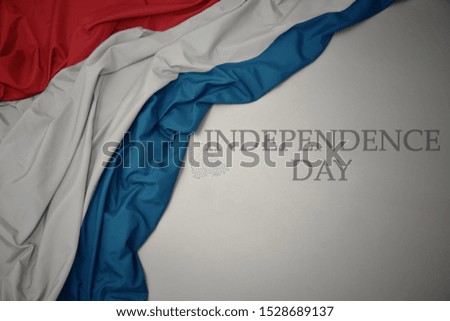 waving colorful national flag of luxembourg on a gray background with text independence day. concept