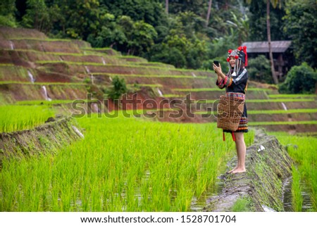 Hmong girl using mobile phone in rice terraces. Ban Pa Bong Piang Northern region in Mae Chaem District Chiangmai Province That has the most beautiful rice terraces in Thailand.