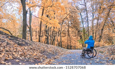 a wheelchair takes pictures of nature in autumn park, fall daylight
