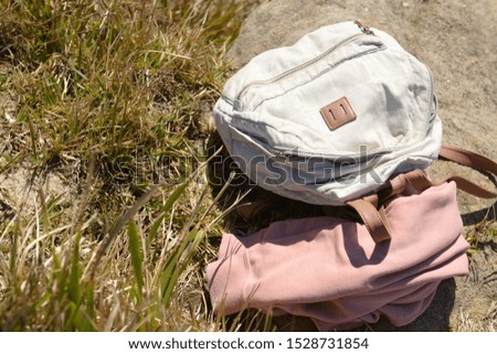 grey backpack with pink hoodie on the grey rock with the sea background 