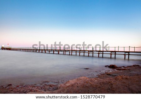 long exposure shot of sea and  a wooden pier structure during sunset, without people