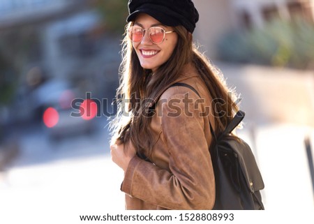 Portrait of pretty young woman looking at camera while standing in the street.