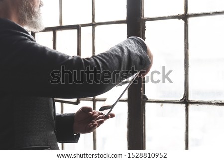 Cropped image with the hands of a mature architect in front of old window. Picture with copy space.
