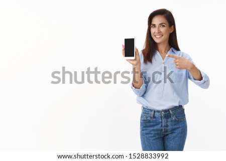 Elegant pleased good-looking cheerful adult lady promote smartphone, hold mobile phone, pointing gadget screen recommend use app, show summer vacation pics display, smiling happily