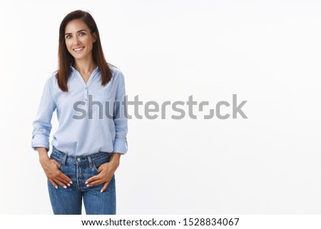 Casual good-looking adult 30s mother keep conversation child teacher, stand relaxed friendly smiling, hold hands loose jeans pockets, look camera amused, standing white background upbeat