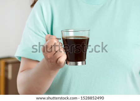 Cropped shot of a woman hand holding a transparent coffee cup at home