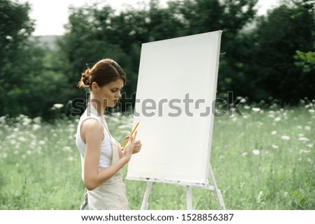 young beautiful woman draws a picture on canvas