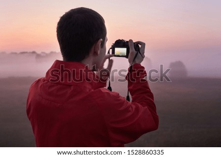A man photographs a dense fog on an early beautiful morning at dawn.