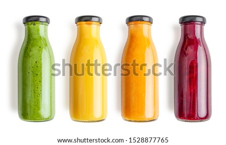 Green, yellow, orange and red smoothie in glass bottles isolated on white background, top view. Clipping path included. Royalty-Free Stock Photo #1528877765
