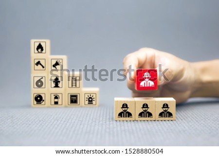 Hand choose wooden block with Firefighter icon for fire and safety Concept.