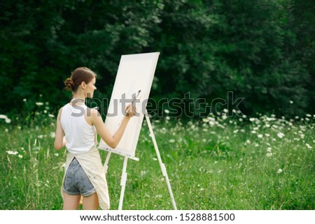 beautiful woman paints a picture on white canvas