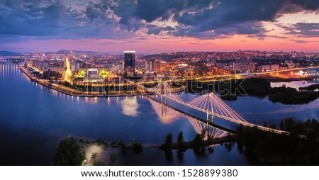 view of the downtown Krasnoyarsk, the bridge through the Yenisei River a sunset, shooting from air Royalty-Free Stock Photo #1528899380