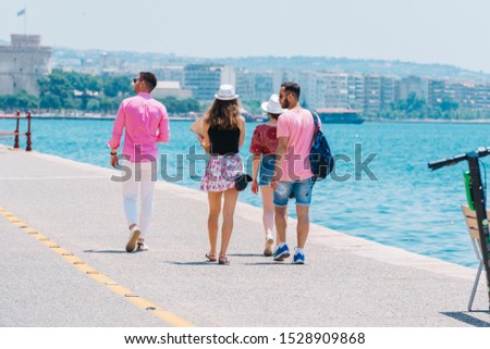 Tourists sightseeing a city while walking on a boardwalk on a sunny summer day.