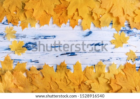 frame composed of yellow and orange autumn leaves on aged wooden background