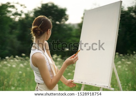 beautiful woman in a forest glade with canvas easel