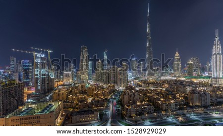 Dubai Downtown skyline night timelapse with building in Dubai and other towers paniramic view from the top in Dubai United Arab Emirates. Traffic on circle road and fountains. Traditional and modern