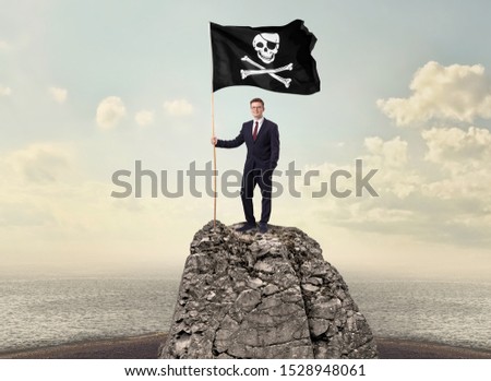 Successful businessman on the top of a mountain holding pirate flag