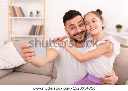 Happy father and child making selfie on cellphone, empty space