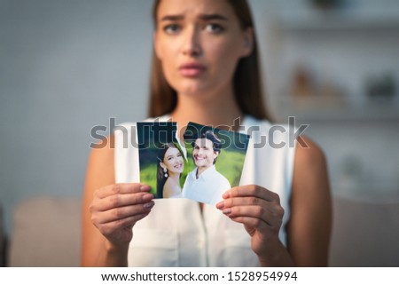 Breakup Concept. Sad Girl Ripping Wedding Photo With Ex-Husband After Divorce Indoor. Selective Focus