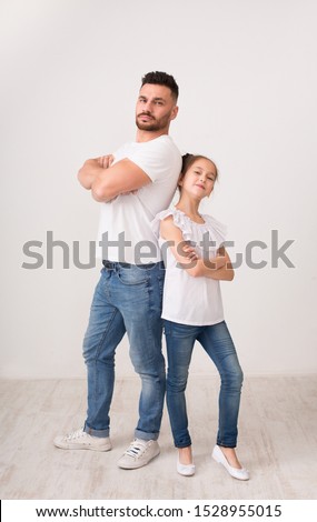 Family friendship. Confident daddy and daughter posing back to back with crossed hands