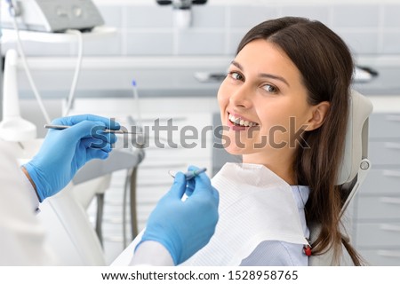Young happy lady sitting in dentist chair, making regular check up in modern clinic, close up, free space Royalty-Free Stock Photo #1528958765
