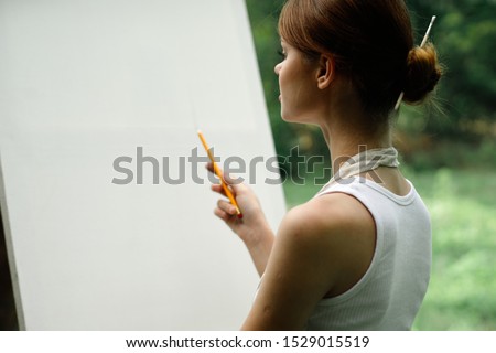 young woman artist paints on white canvas