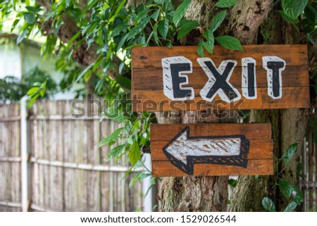 Signs made of wood have the English alphabet written "Exit" and have an arrow symbol to indicate the parking area.Background is blurred.