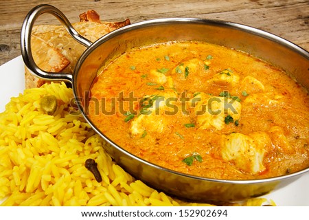 Chicken Korma a popular sweet indian curry dish of coconut and cream sauce served in a dish on a plate with pilaf rice and samosas Royalty-Free Stock Photo #152902694