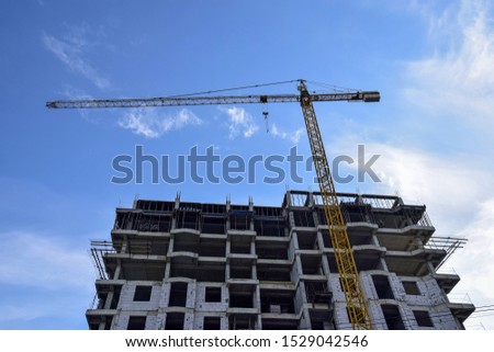 Construction of a new residential building  with use of tower crane against Blue Sky. Real Estate, Residential Buildings Urban Mixed-Use Development Concept. Royalty-Free Stock Photo #1529042546