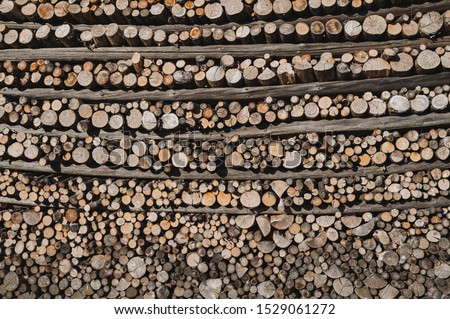 In precise order folded firewood in between horizontal crossbars of a hayrack.