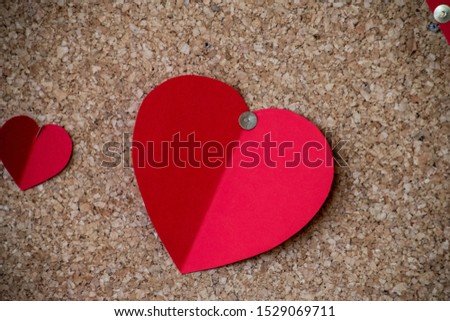 beautiful colorful cut out paper hearts on a brown cork background,