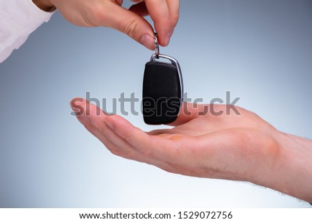 Close-up Of A Car Salesman Handing Over The New Car Key To The Owner's Hand