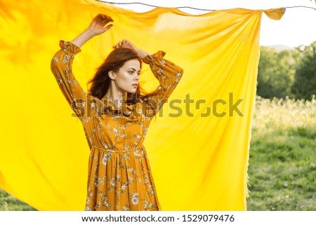 young woman in a yellow dress looking at the camera with a cloth