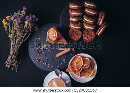 Baking background with chocolate cake, a cup of coffee, biscuits, dried citrus, on dark  background. Flat lay with copy space. view from above.
