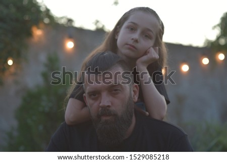 Family time. Little girl hugging her dad with a beard. Summer walk. Child girl with blond hair rejoices with a parent. The most valuable time is the time spent with your beloved family. Childhood