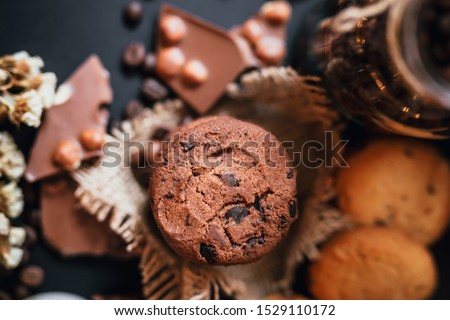 Shortbread chocolate cookies and a cup of hot coffee on a dark background. 
Milk chocolate with nuts and cookies.  Coffee beans on black backround.