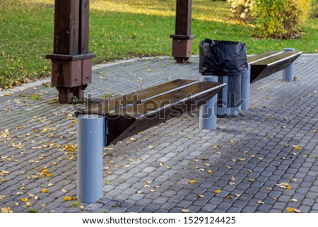 Two wooden benches in a park or garden on a background of green trees and grass