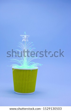 Luminous white artificial spruce in yellow flowerpot on blue background. New year concept. Place for text