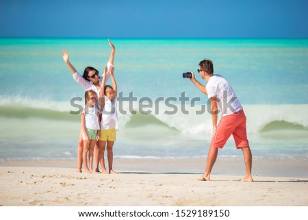 Man taking a photo of his family on the beach vacation
